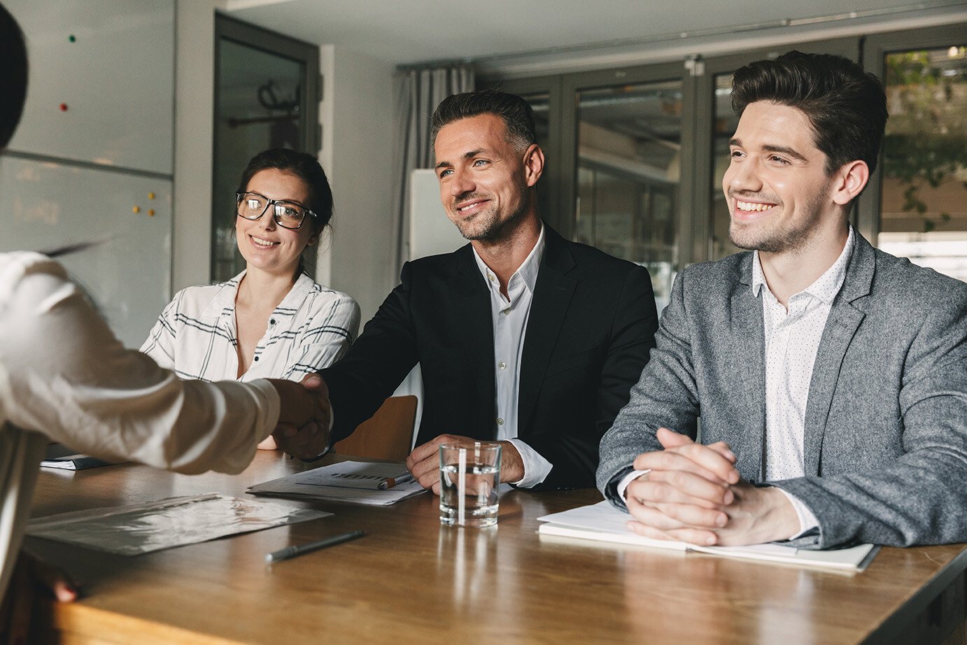 business-executives-shaking-hands-across-table-as-208777699