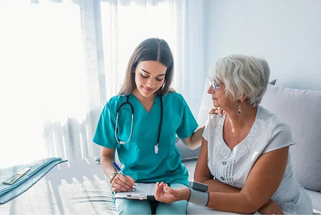 Healthcare provider writing on clipboard while attending to a patient