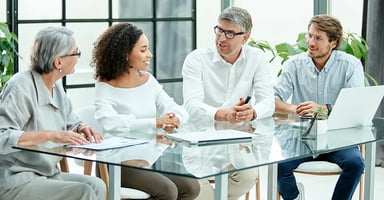 Several business professionals talking around a glass conference table